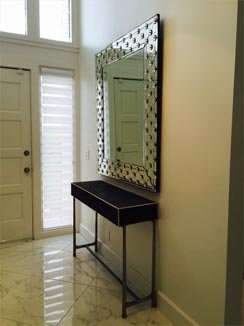 framed mirror over table by entrance