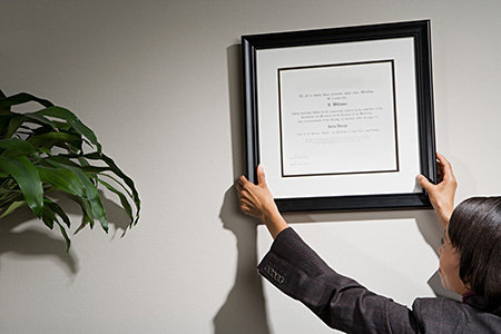 person hanging a framed diploma